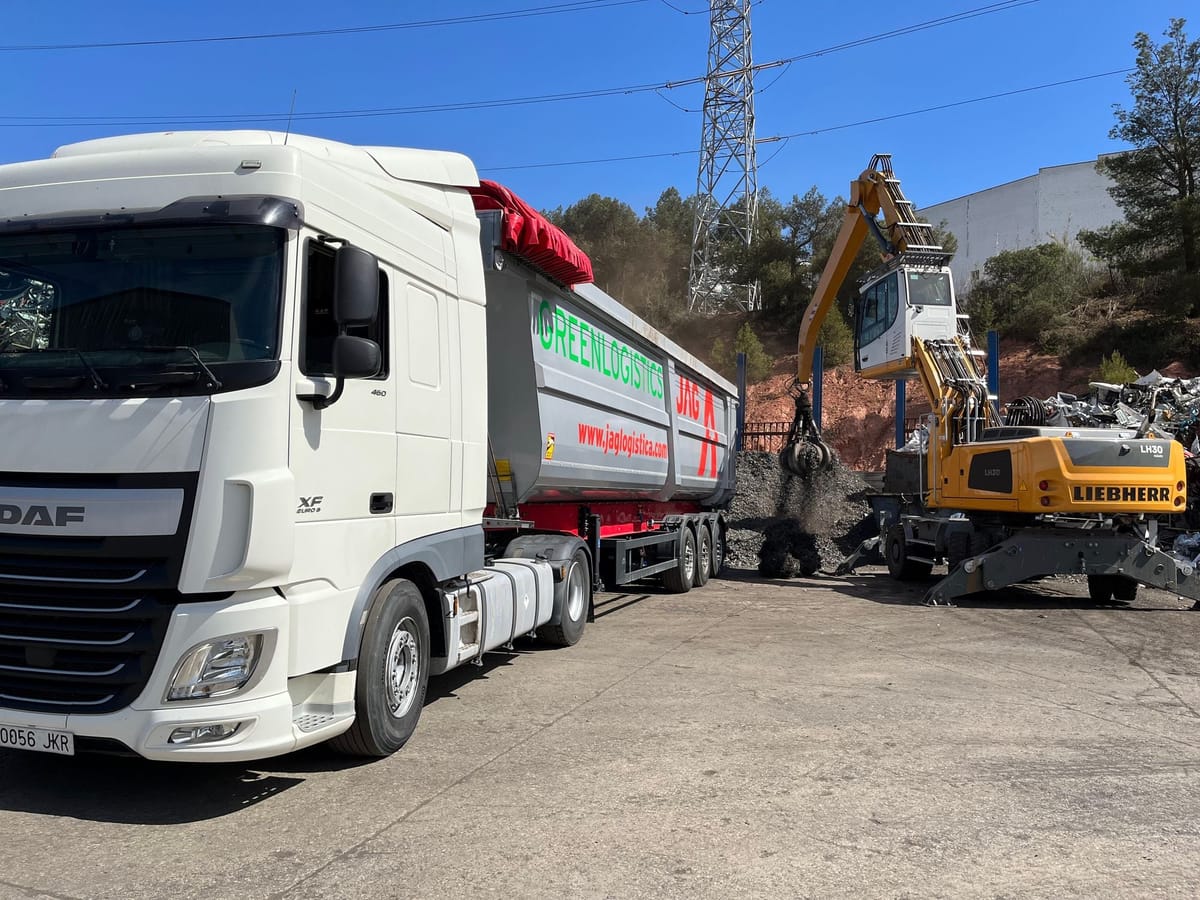JAG truck with its tipper raised, unloading scrap next to a pile of metal waste
